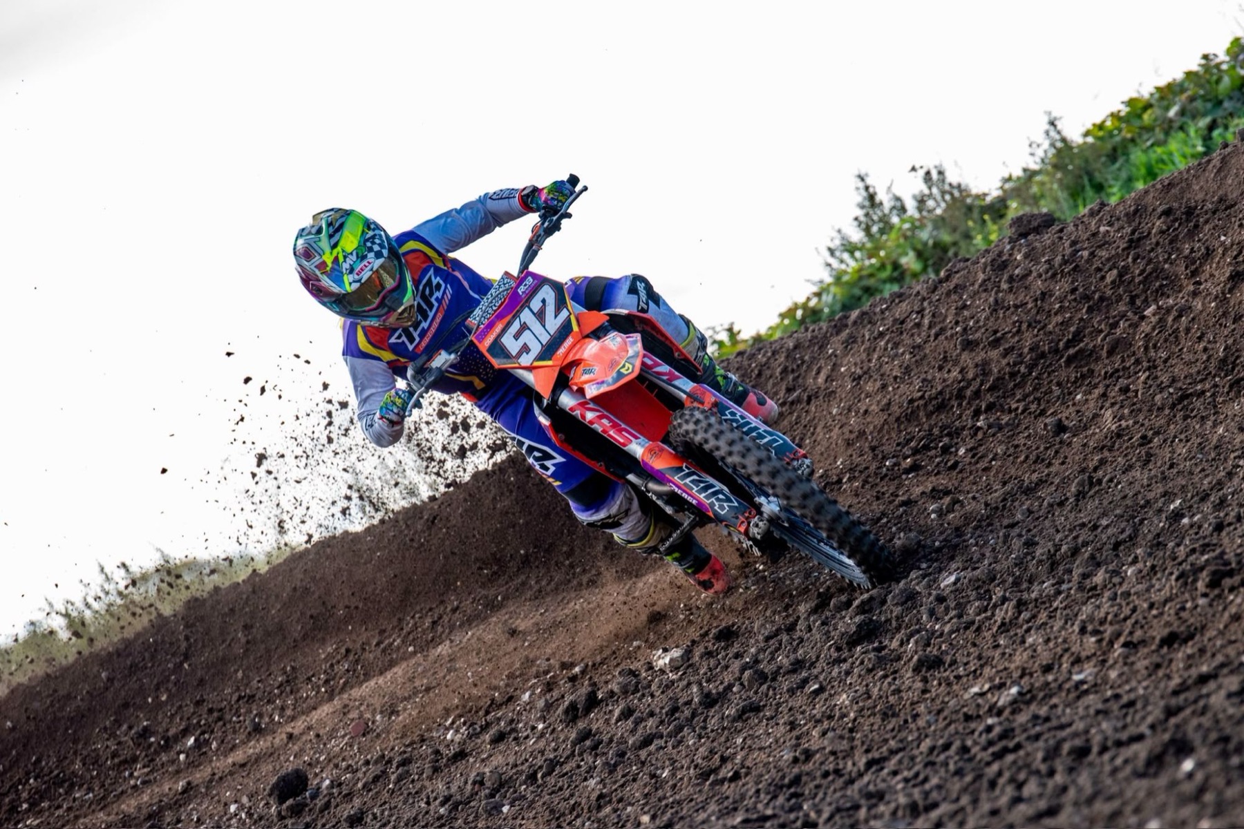 Motocross rider throwing up dirt as they rail a steep berm